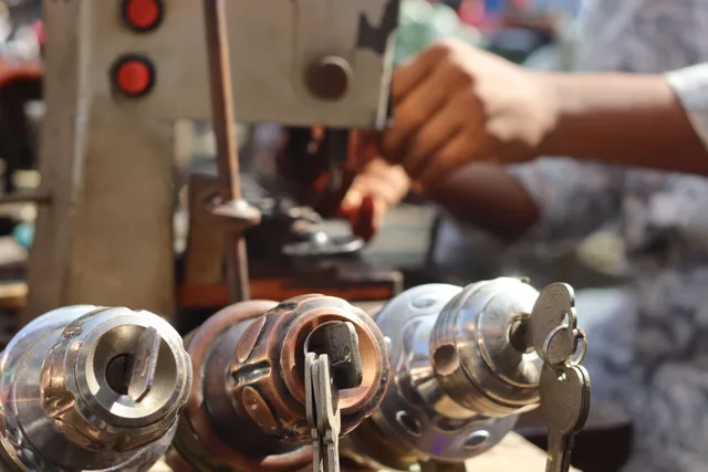 Close-up image of locksmith tools and hands working with a key machine outdoors. How to figure out which locksmith service lines are profitable